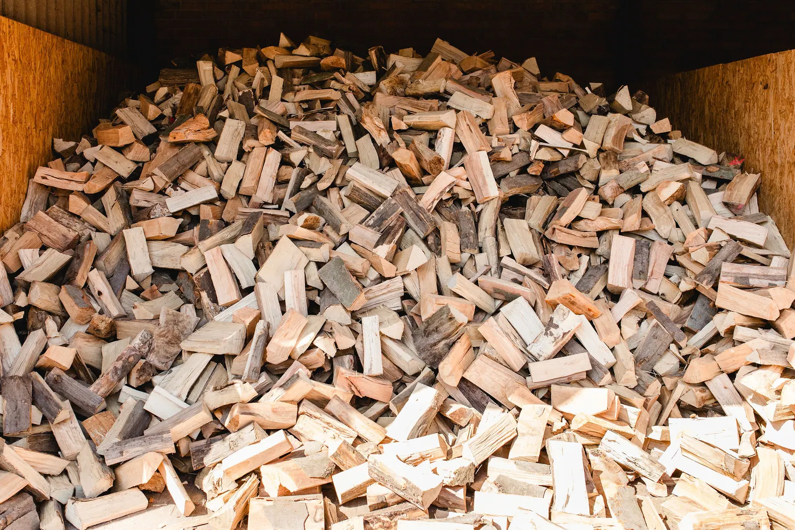 Lose aufgeschüttete Kaminholzscheite im überdachten Holzlager
