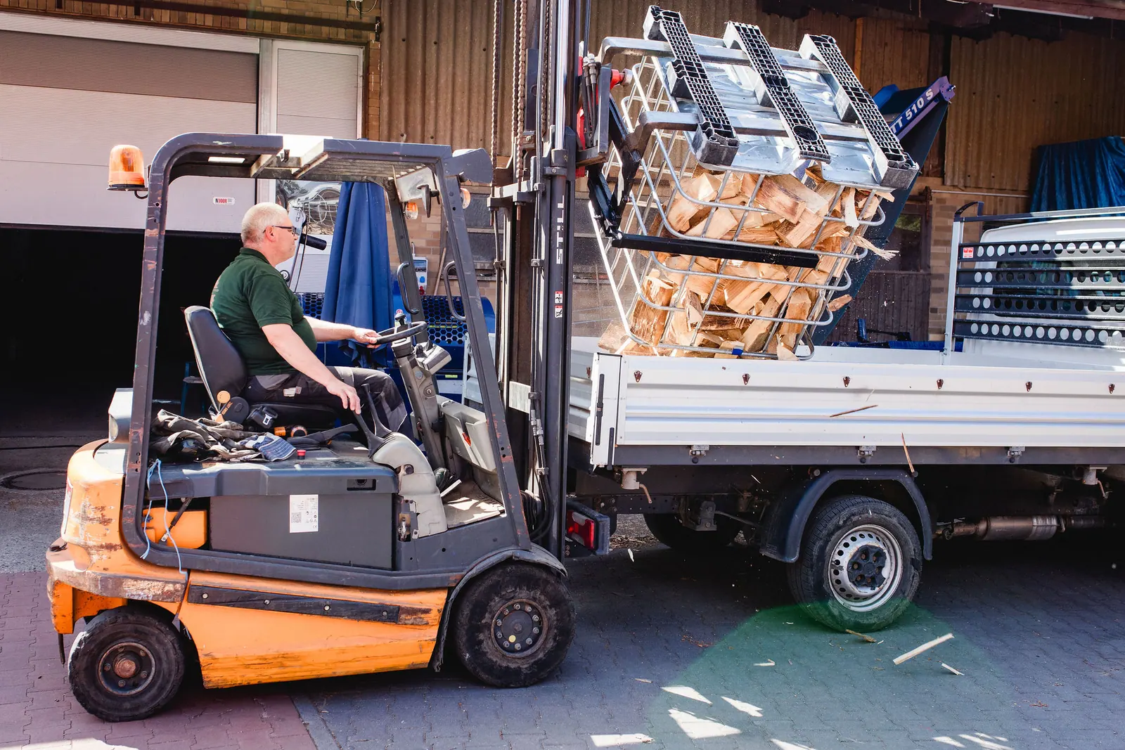 Karsten Garbe kippt mit dem Gabelstapler Kaminholz aus einer Gitterbox auf den Transporter